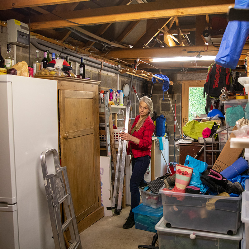 A mature woman moving things in her garage whilst at home