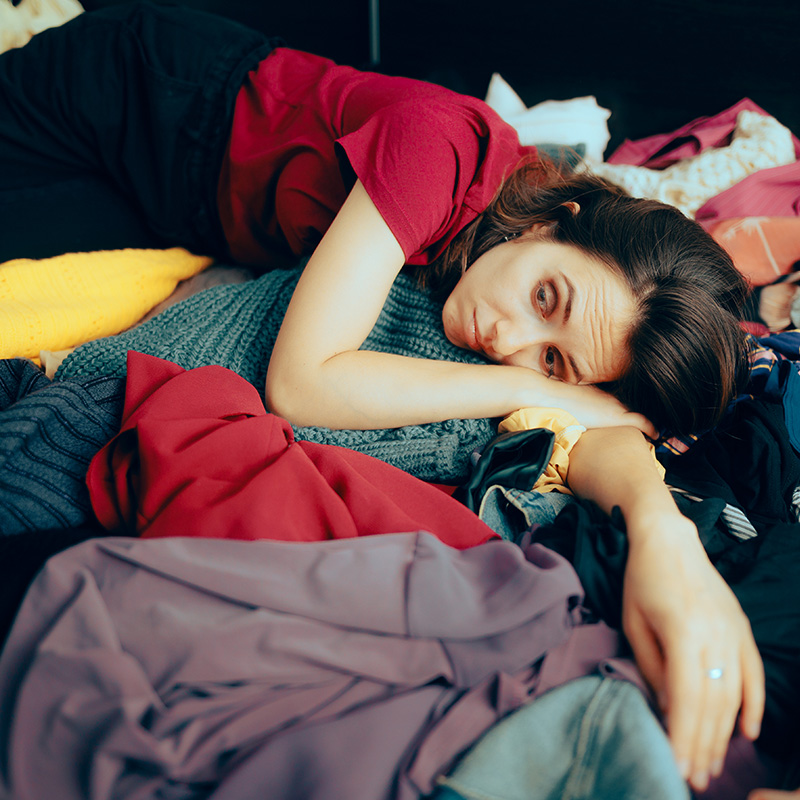 Unhappy Woman Sitting on a Pile of Clothes